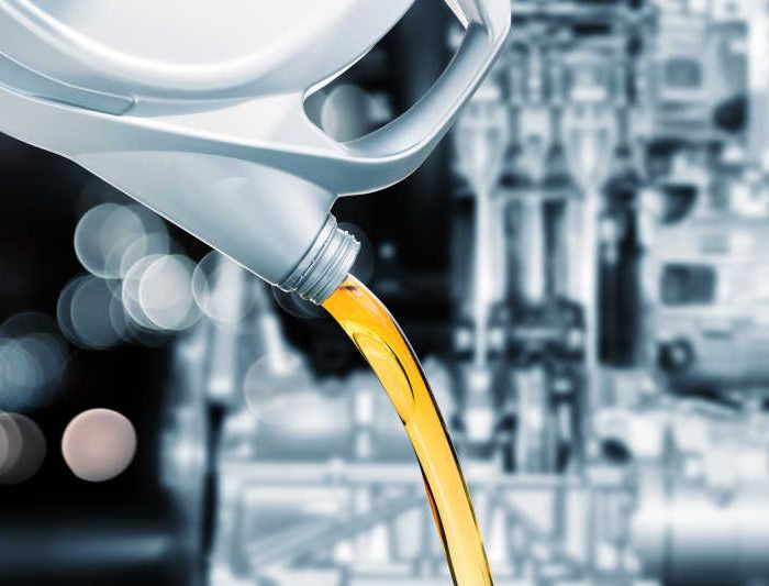 Pouring motor oil on engine background